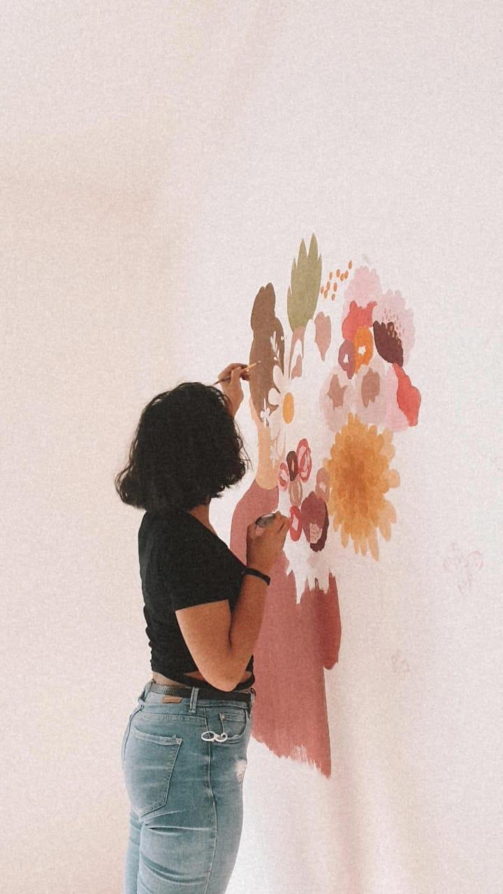 A volunteer painting a floral bouquet mural